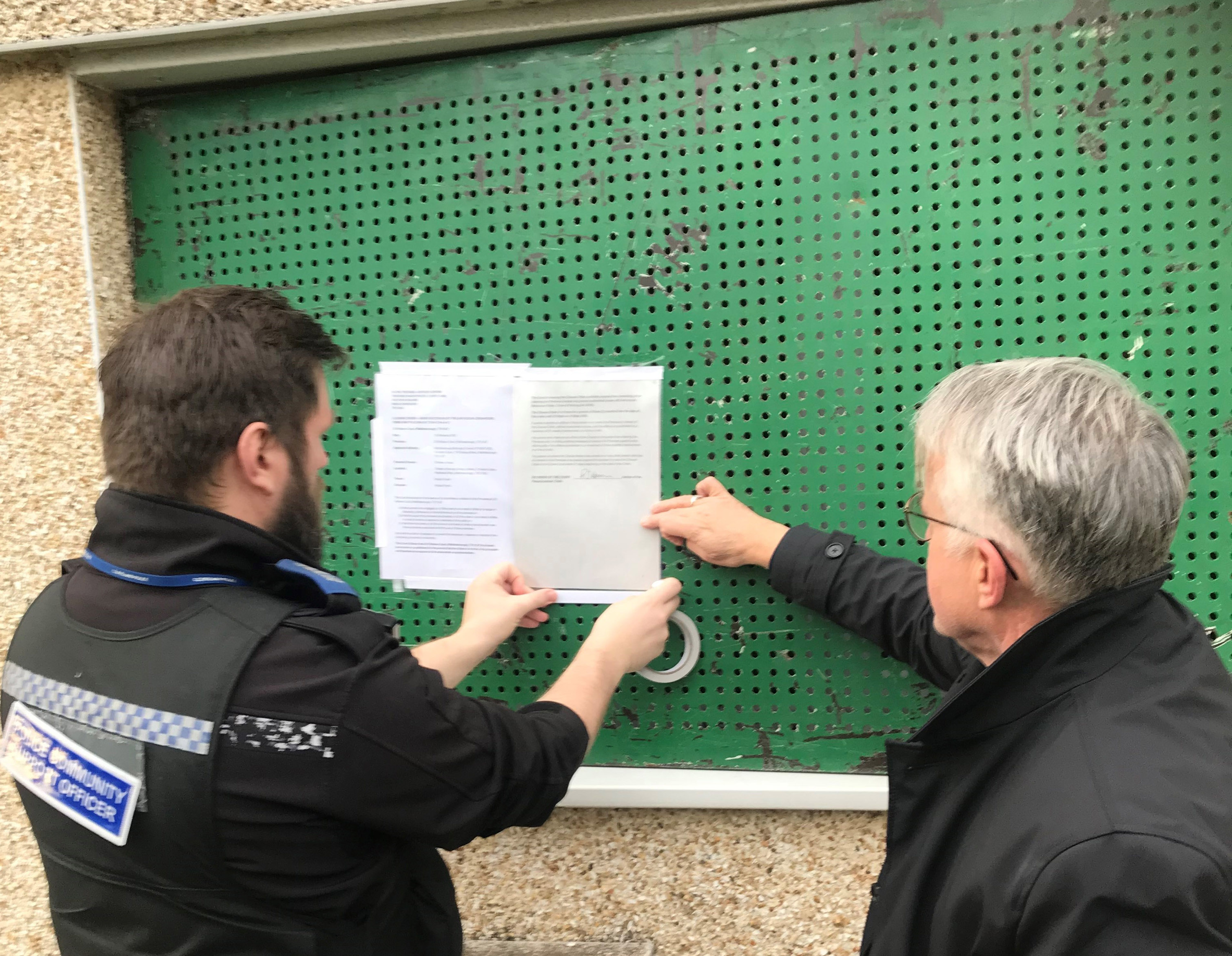 PCSO Steve Cook from Cleveland Police and Neighbourhood Safety Officer Hugh McShane of Middlesbrough Council’s Safer Communities Service attach a closure notice to the flat at Fallows Court following a successful application to Teesside Magistrates