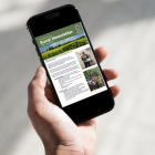 Hand holding a phone, which displays the latest rural crime newsletter
